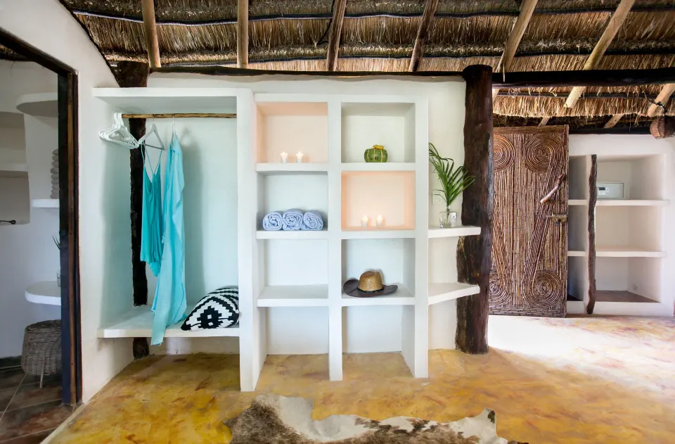 Triple Room at Amansala open shelving and hanging wardrobe area with colorful garments and thatched ceiling