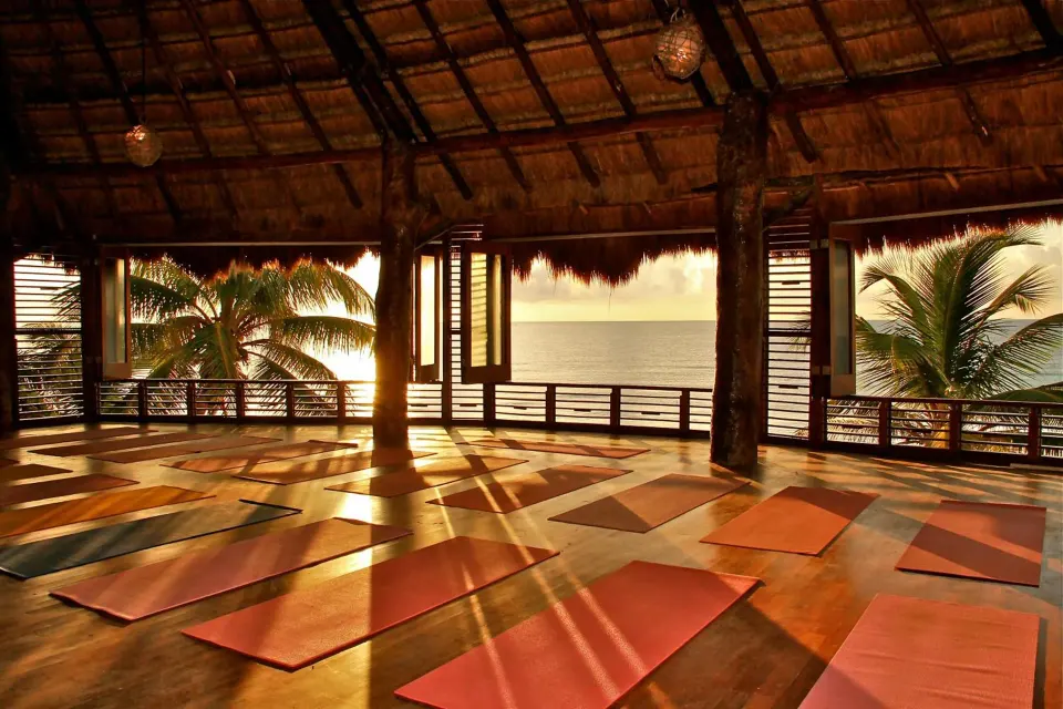 Open thatched yoga pavilion with mats facing the ocean at Amansala