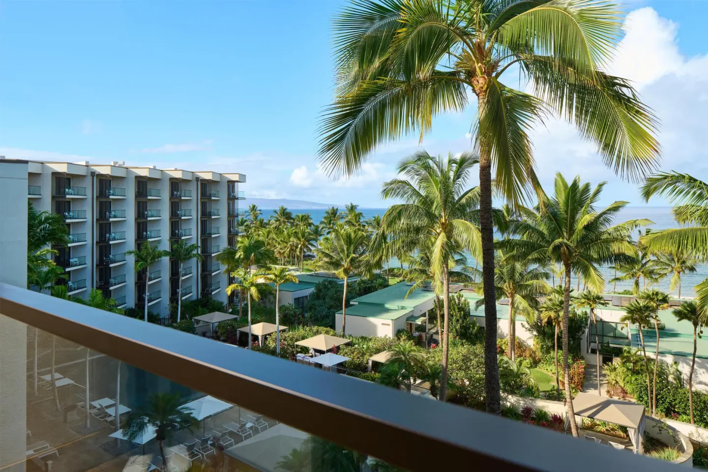 Balcony view over palms, resort buildings, and the ocean at Andaz Maui at Wailea Resort.