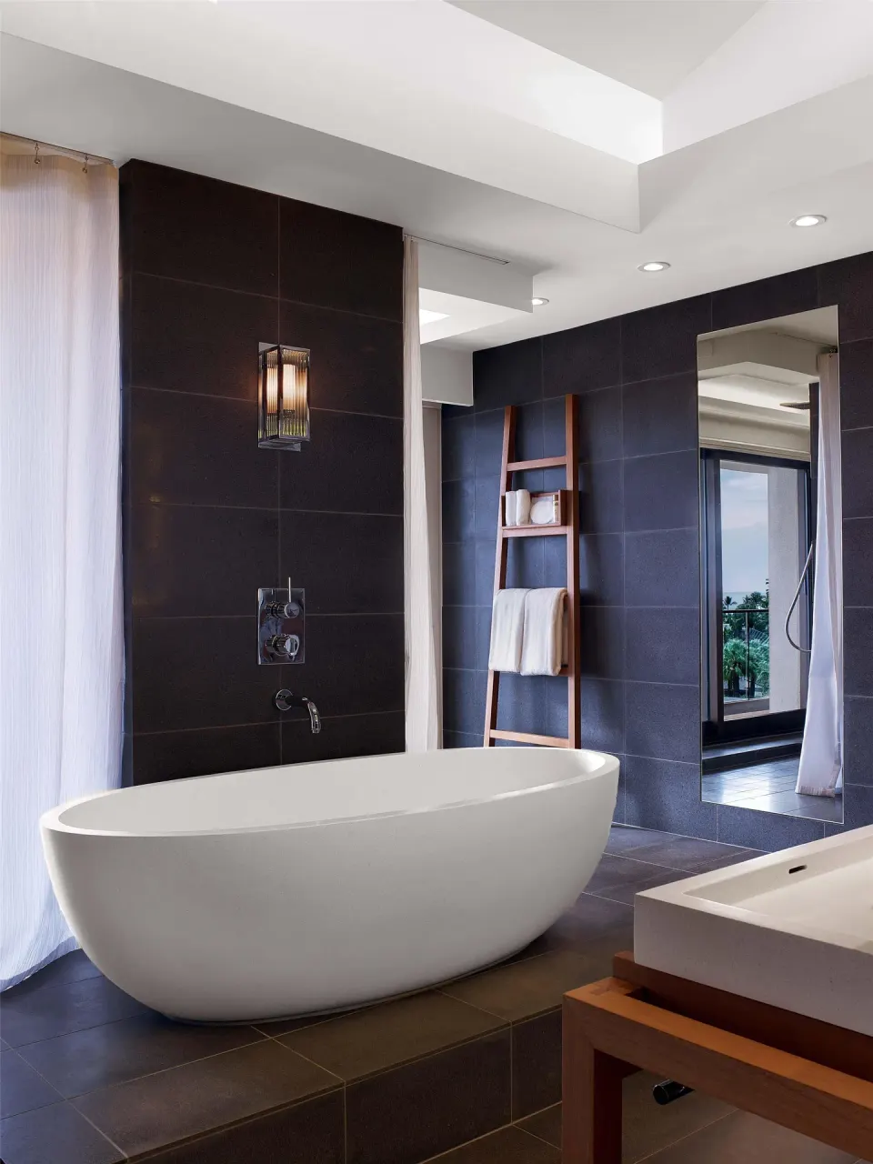 Bathroom with freestanding tub and dark tile walls at Andaz Maui at Wailea Resort.