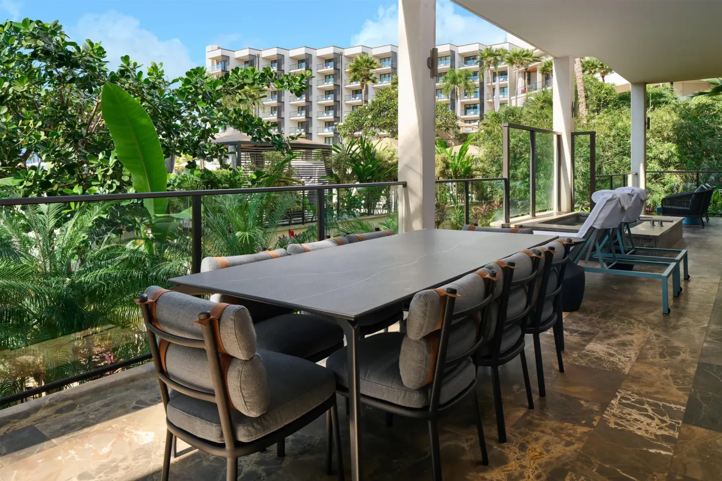 Covered terrace dining table and lounge chairs at Andaz Maui at Wailea Resort.