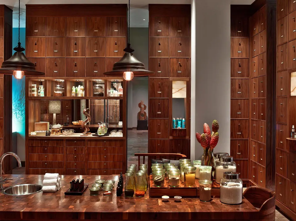 Spa apothecary counter with jars, candles, and wood cabinetry at Andaz Maui at Wailea Resort.