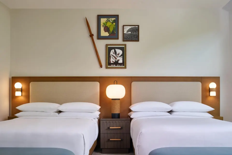 Villa bedroom with two beds, bedside lamps, and wall art at Andaz Maui at Wailea Resort.