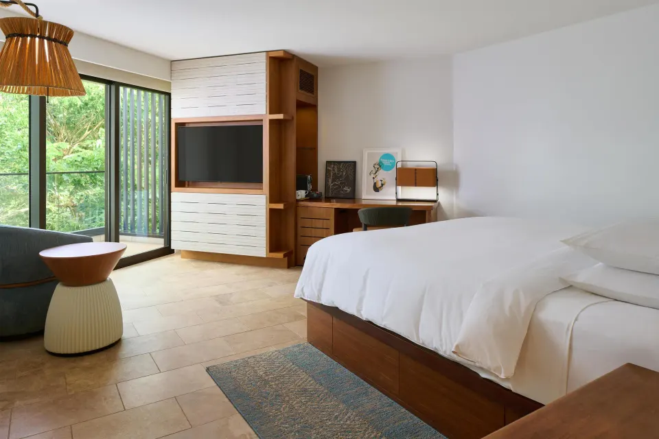 Guest room with king bed, TV wall, desk, and balcony greenery at Andaz Maui at Wailea Resort.