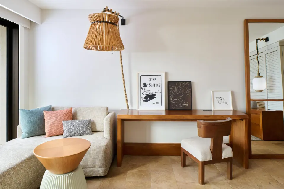 Guest room sitting area with sofa, desk, and woven lamp at Andaz Maui at Wailea Resort.