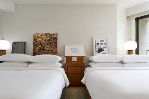 Two queen beds with bedside lamps and wall art at Andaz Maui at Wailea Resort.
