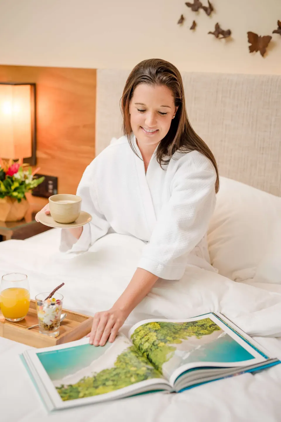 Guest in a white robe enjoys breakfast in bed at Andaz Peninsula Papagayo Resort, Costa Rica.