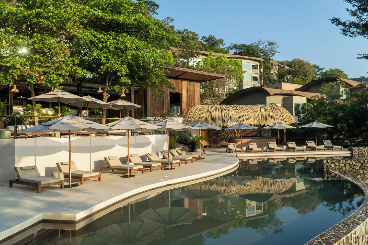Curved pool deck with loungers and umbrellas at Andaz Peninsula Papagayo Resort, Costa Rica.