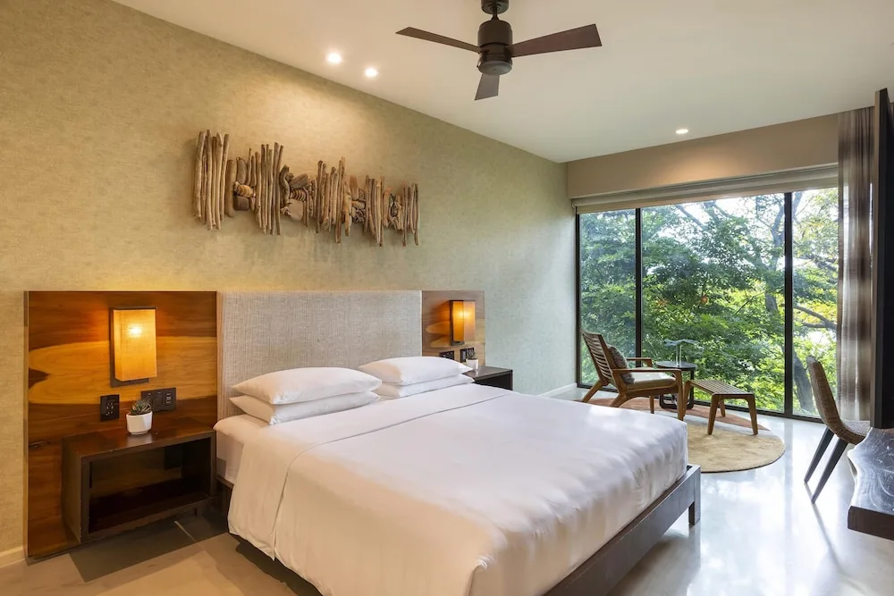 King bed beside large windows in a guest room at Andaz Peninsula Papagayo Resort, Costa Rica.
