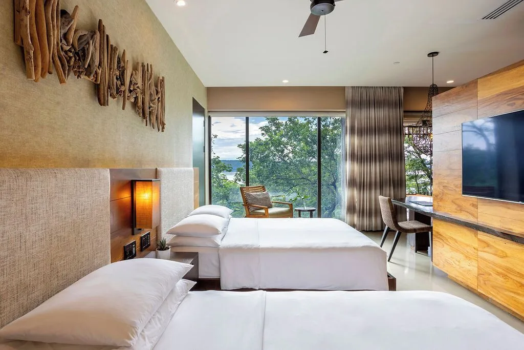 Two beds and floor-to-ceiling windows in a guest room at Andaz Peninsula Papagayo Resort, Costa Rica.