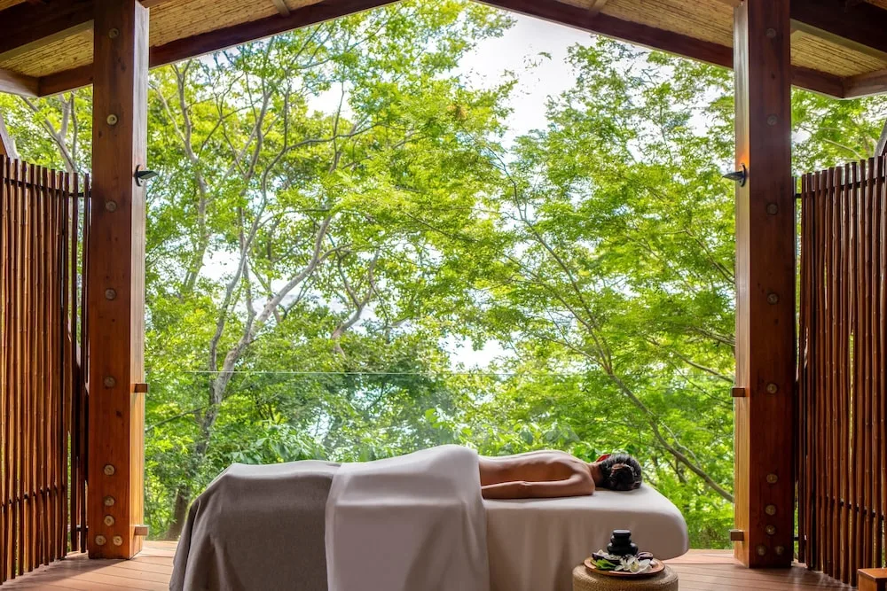 Outdoor massage table framed by green trees at Andaz Peninsula Papagayo Resort, Costa Rica.