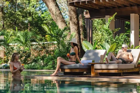 Guests relax on pool loungers and in the water at Andaz Peninsula Papagayo Resort, Costa Rica.