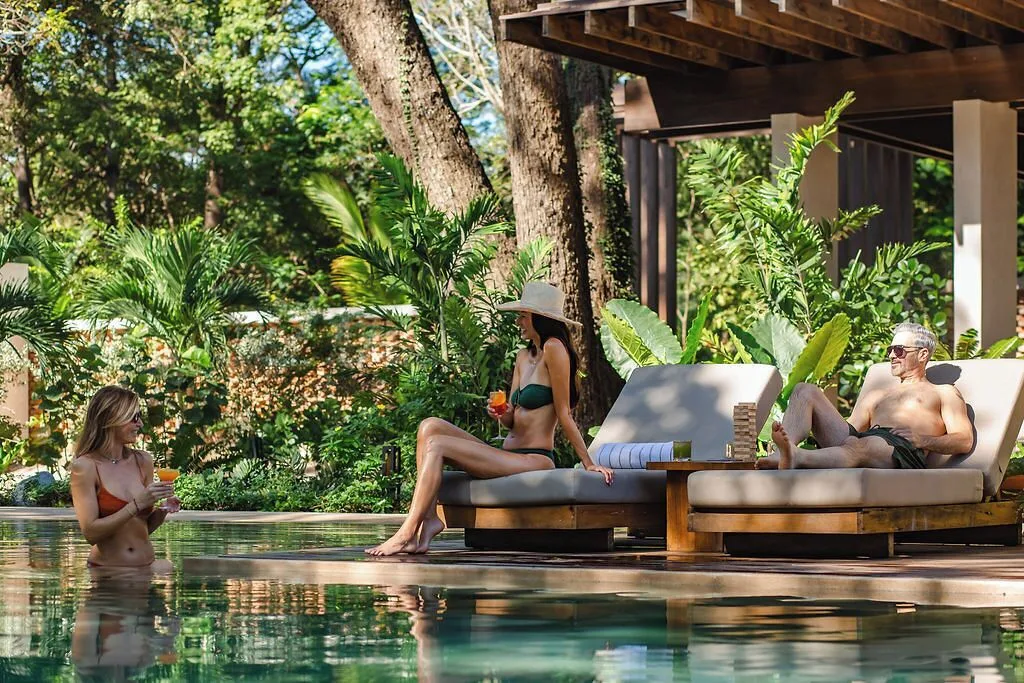 Guests relax on pool loungers and in the water at Andaz Peninsula Papagayo Resort, Costa Rica.