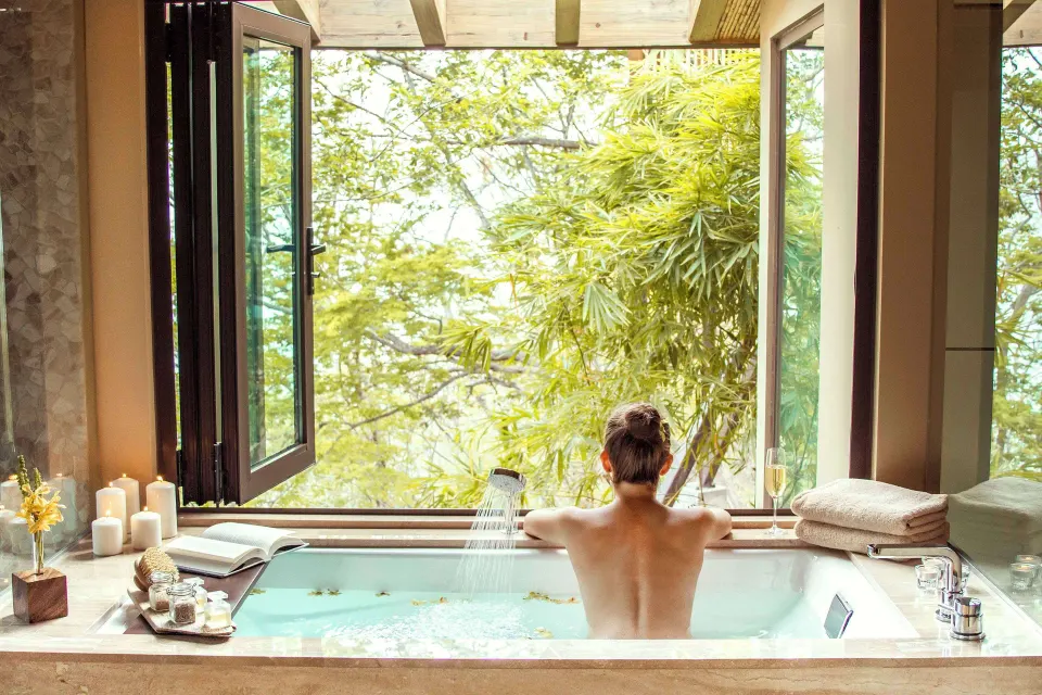 Guest soaking in a tub by open windows at Andaz Peninsula Papagayo Resort, Costa Rica.