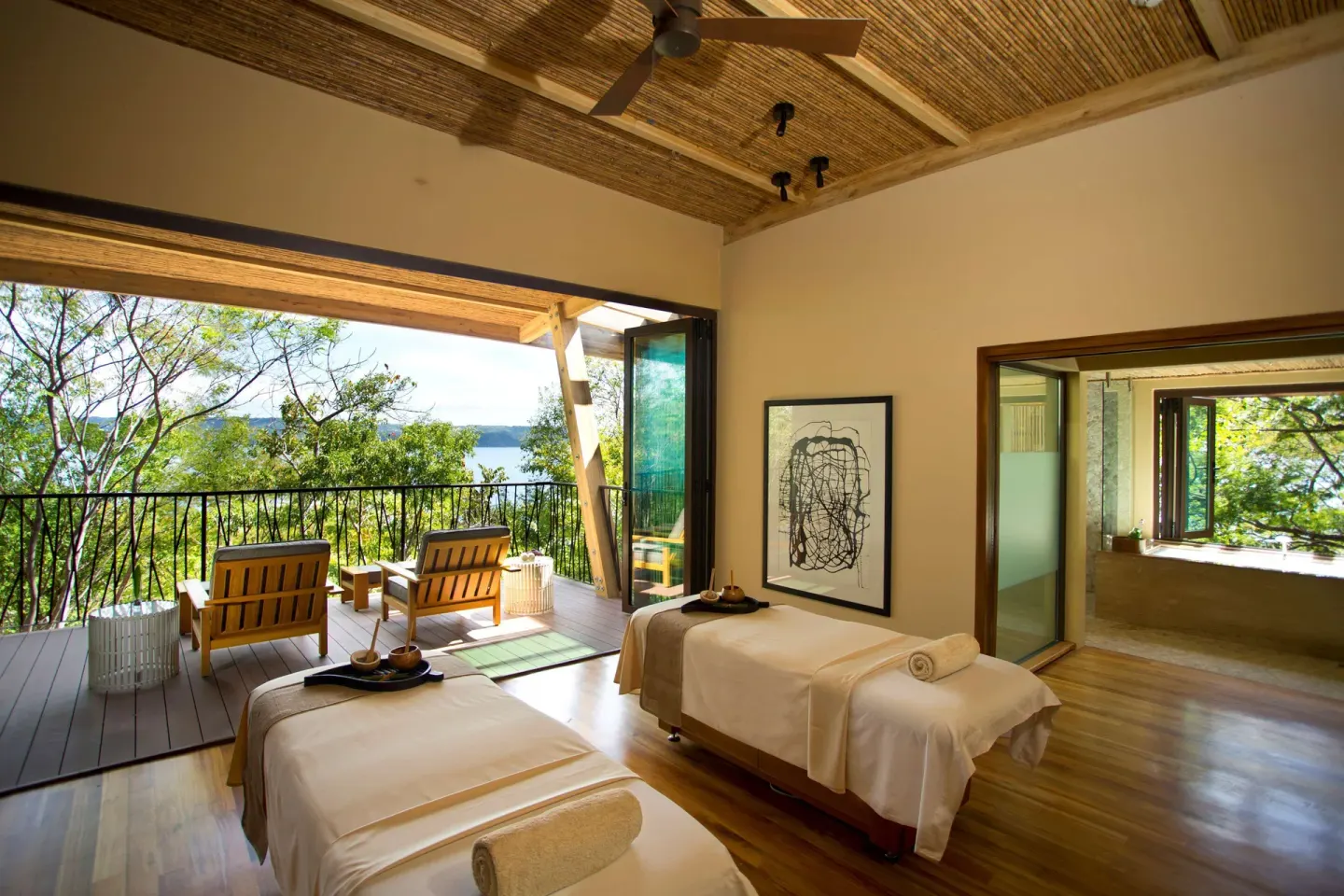 Spa treatment room with two massage tables and balcony at Andaz Peninsula Papagayo Resort, Costa Rica.