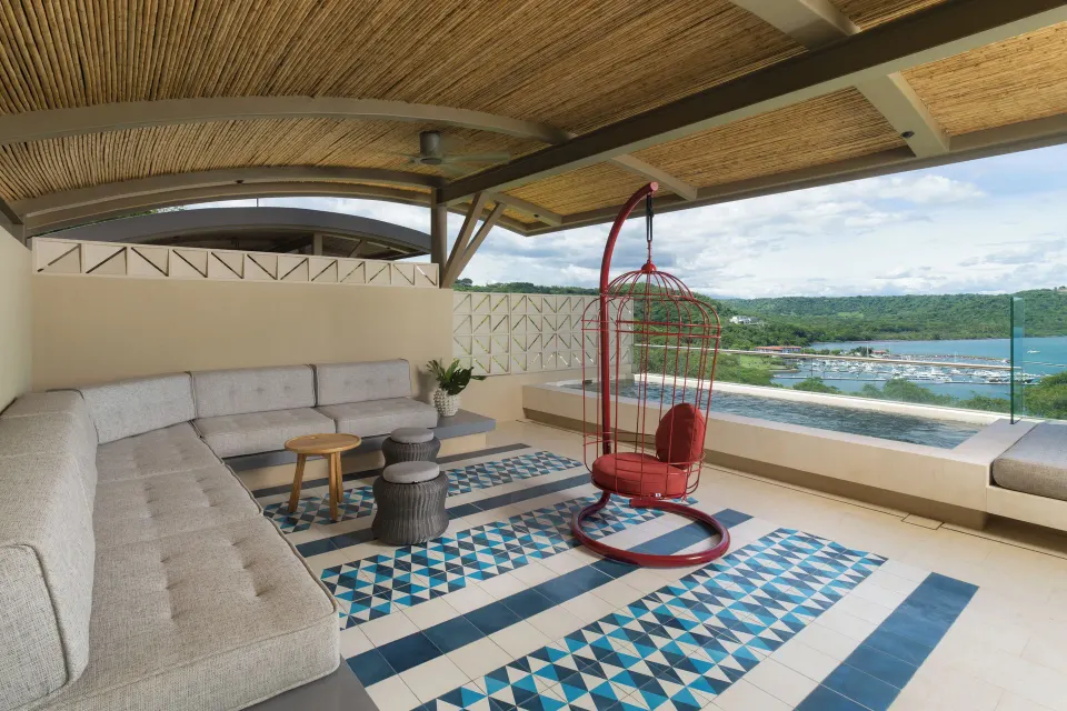 Covered penthouse terrace with hanging chair and pool at Andaz Peninsula Papagayo Resort, Costa Rica.