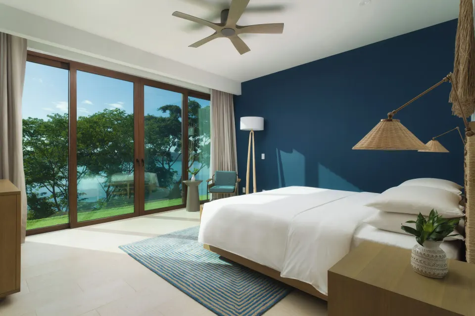 King bedroom with blue wall and water view at Andaz Peninsula Papagayo Resort, Costa Rica.