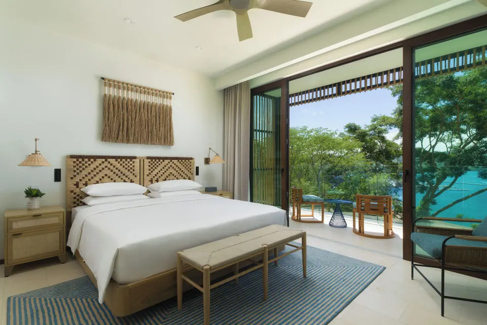 King penthouse bedroom with terrace chairs and bay view at Andaz Peninsula Papagayo Resort, Costa Rica.