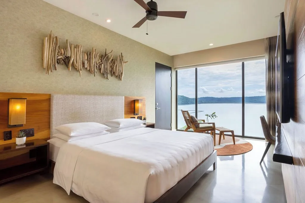 Bay View king guest room with driftwood art and bay-facing windows at Andaz Peninsula Papagayo Resort, Costa Rica.