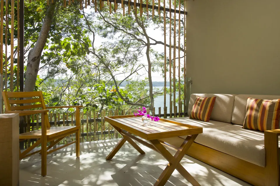 Forest view terrace at Andaz Peninsula Papagayo Resort, Costa Rica with sofa, table, and trees outside.