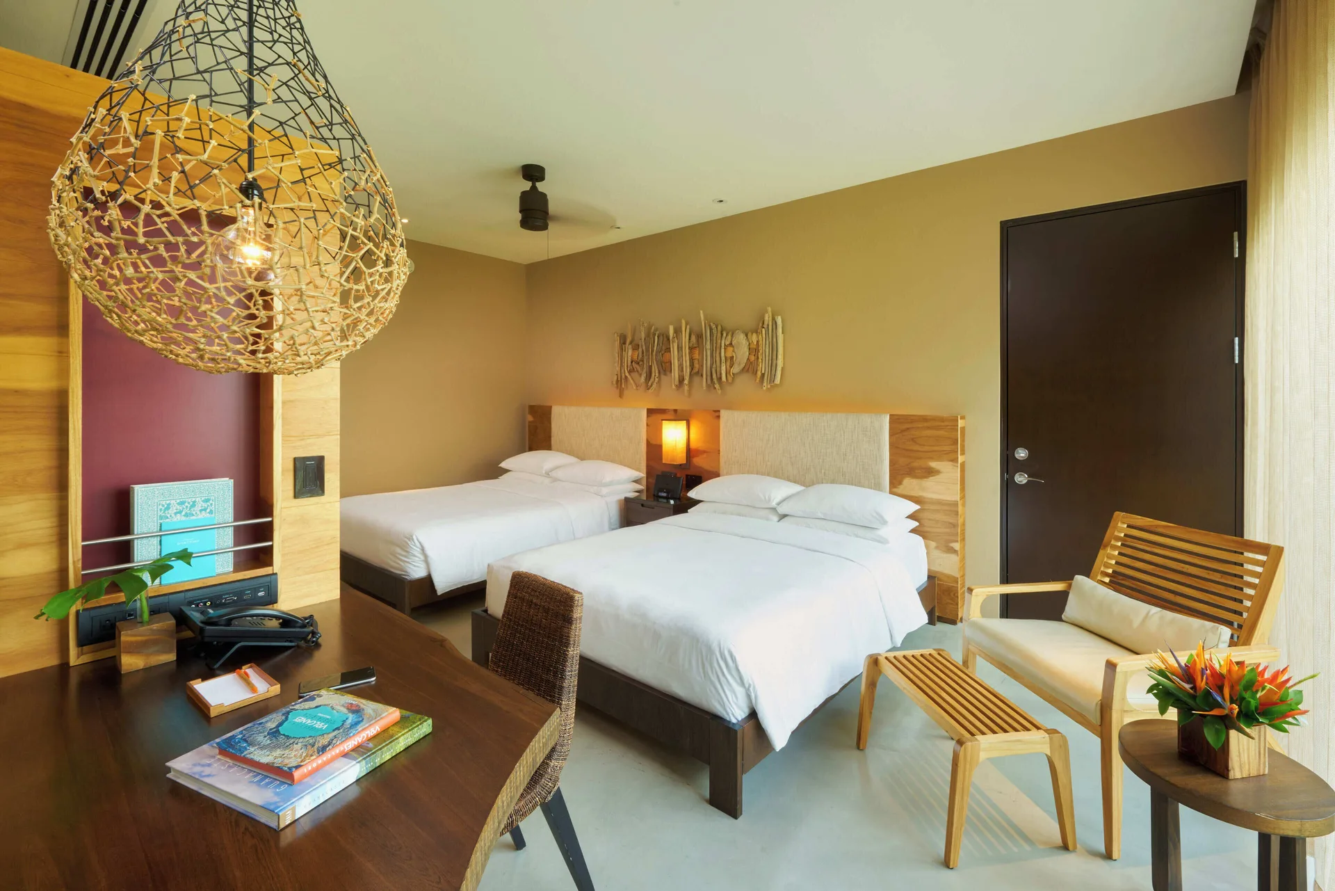 Two-bed forest view guest room at Andaz Peninsula Papagayo Resort, Costa Rica with desk and lounge chair.