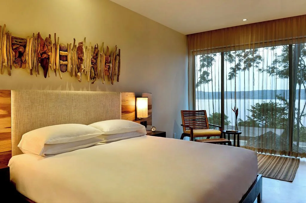 King bed by glass doors with bay view at Andaz Peninsula Papagayo Resort, Costa Rica.