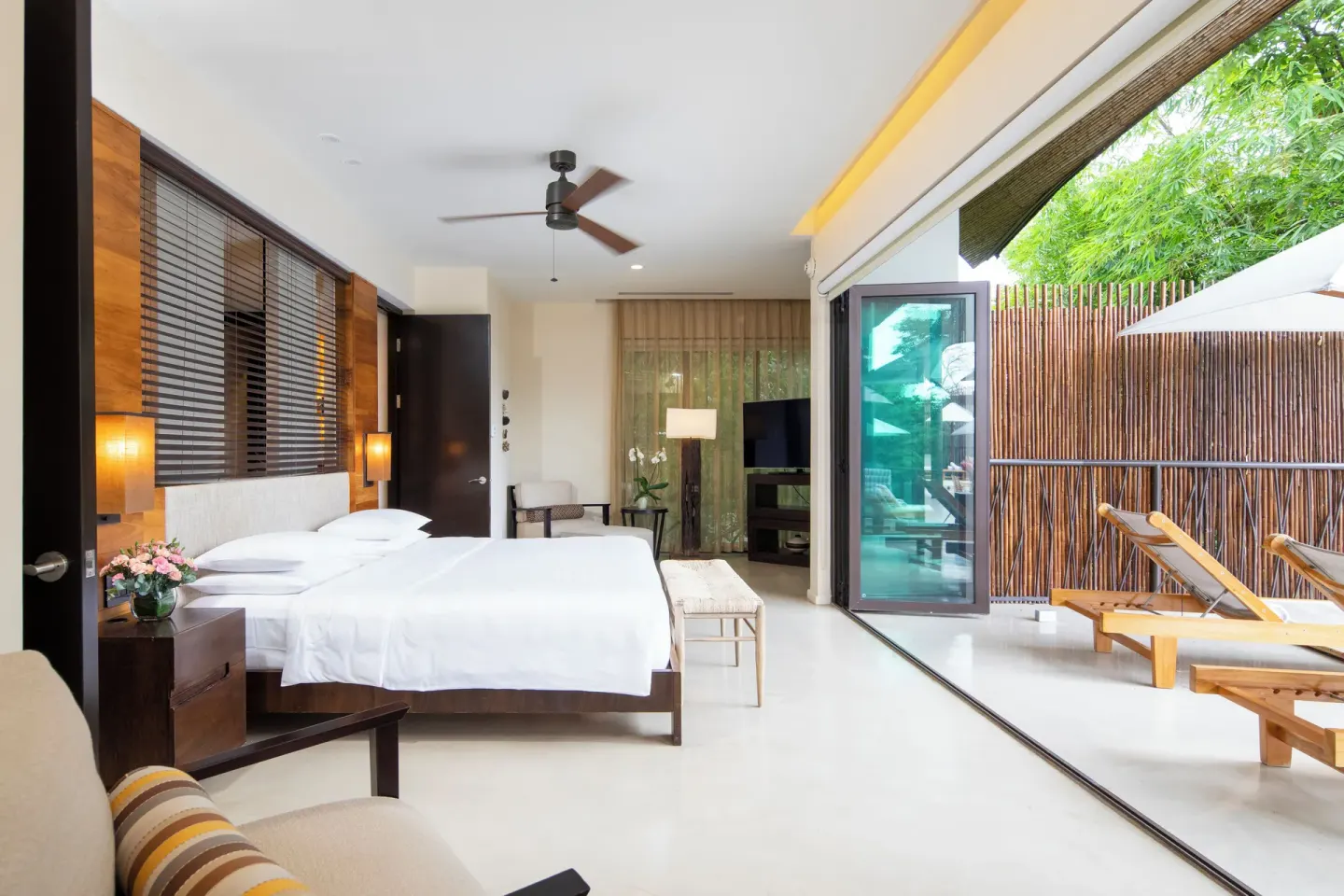 Pool suite bedroom with king bed and terrace loungers at Andaz Peninsula Papagayo Resort, Costa Rica.