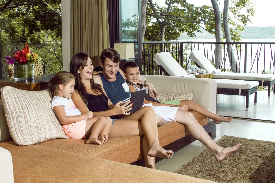 Family seated on a suite sofa by the terrace at Andaz Peninsula Papagayo Resort, Costa Rica.