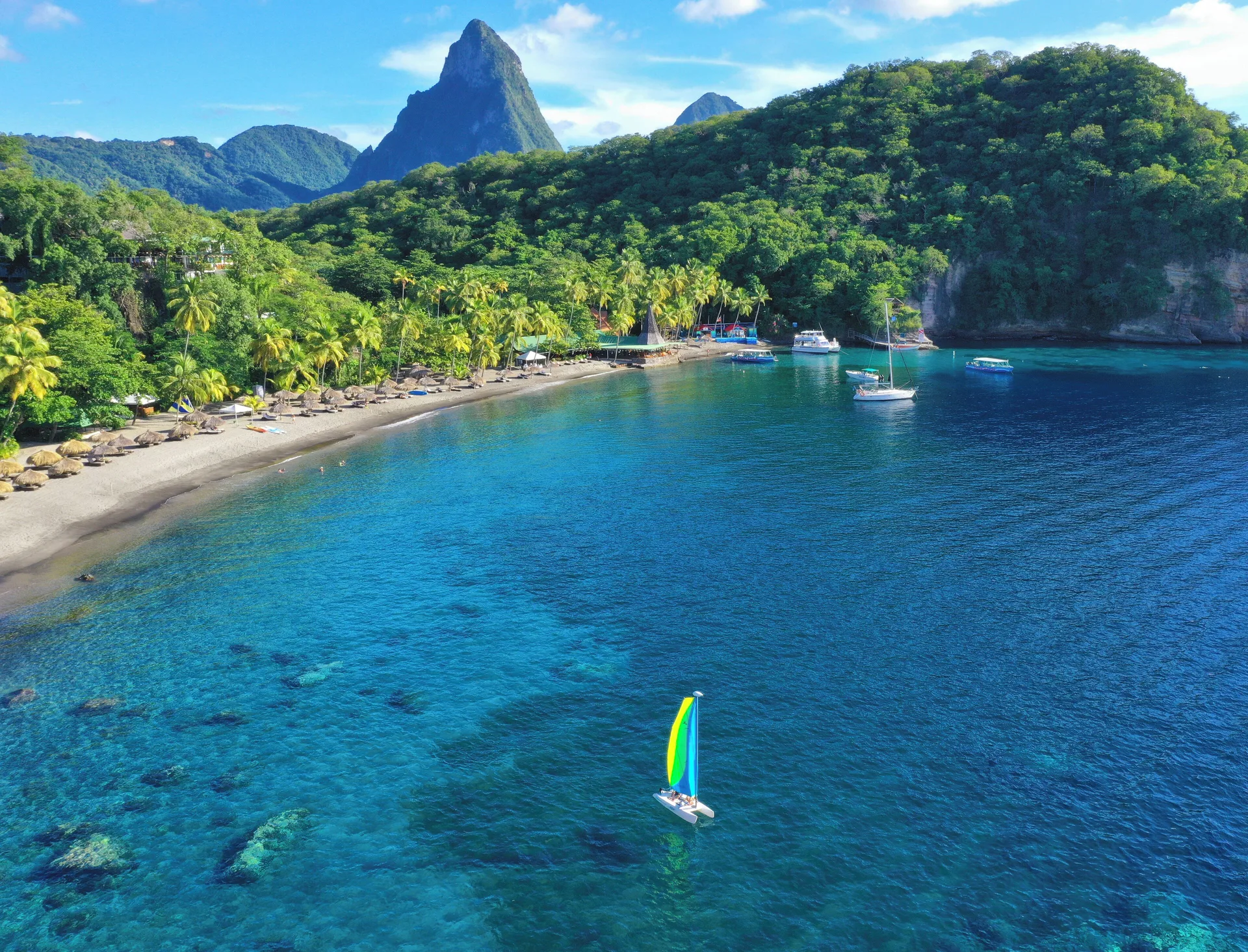 Aerial bay view with sailboat, beach and Piton backdrop at Anse Chastanet Resort.