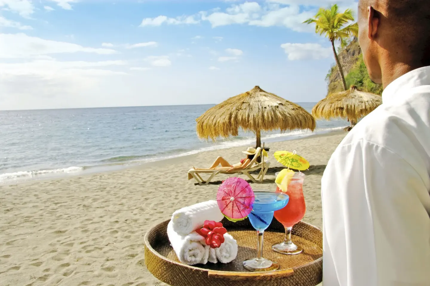 Server carries tropical drinks and towels on the beach at Anse Chastanet Resort.