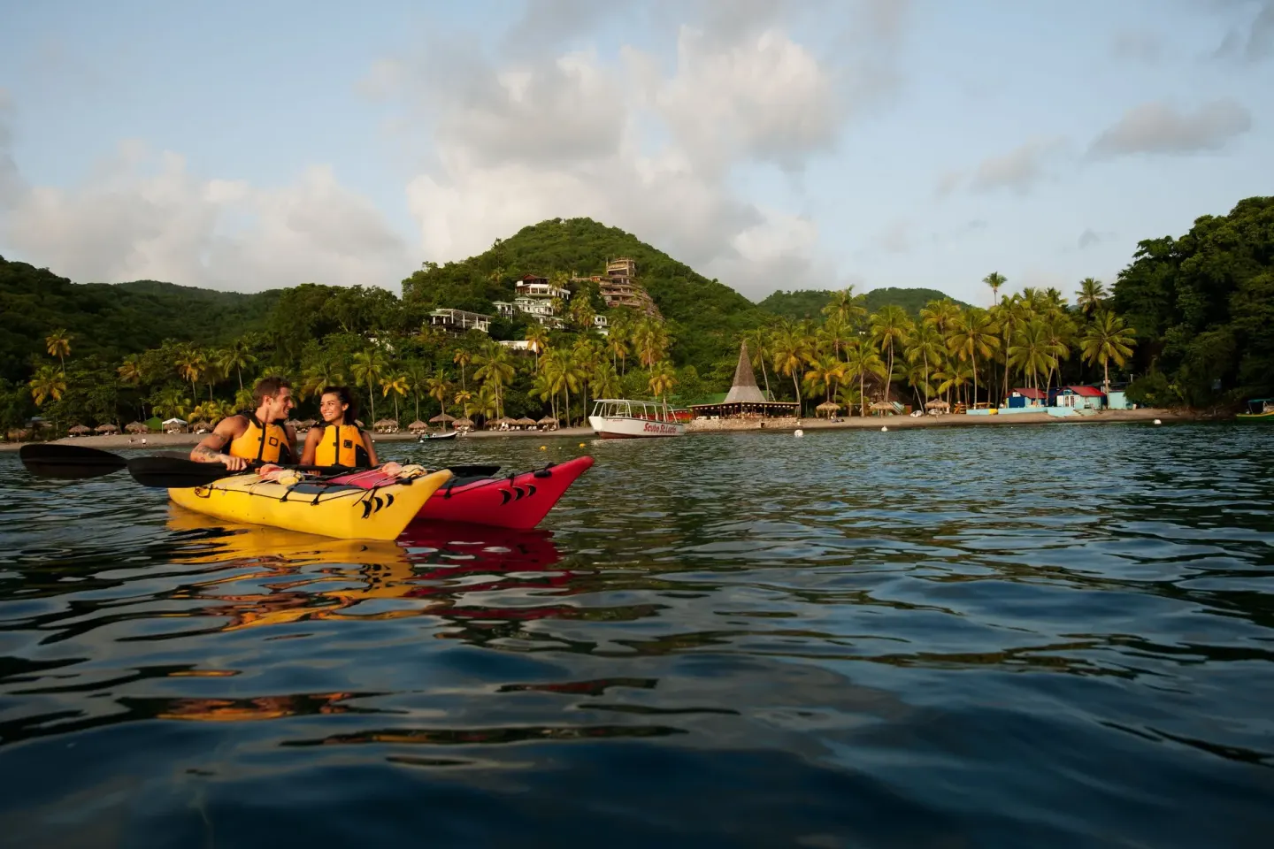 Kayakers float offshore with the beach and hillside at Anse Chastanet Resort behind them.