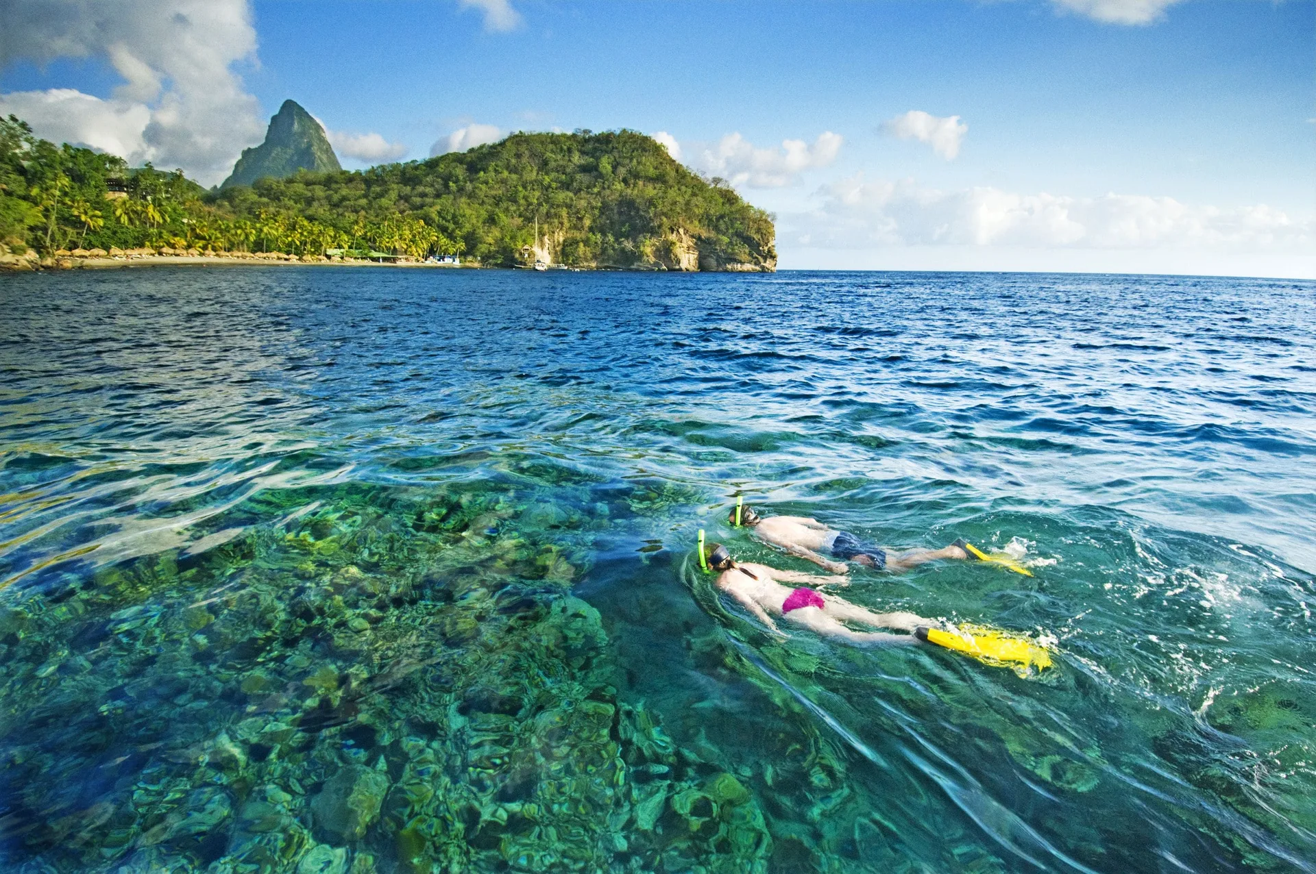 Two snorkelers swim over clear reef water near Anse Chastanet Resort.