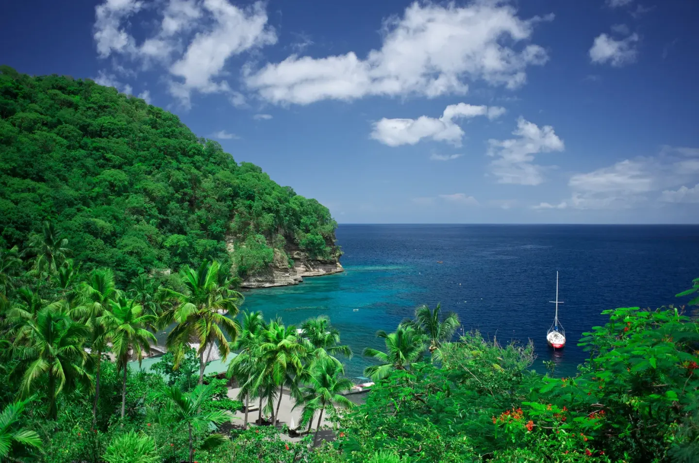 Tropical hillside and bay overlook a sailboat near Anse Chastanet Resort.