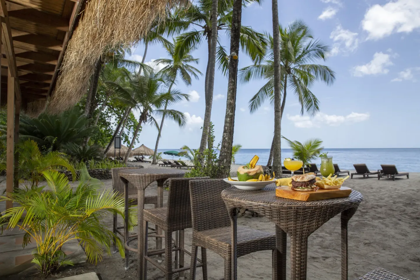 Beachside table with burgers, drinks, palms and sea at Anse Chastanet Resort.