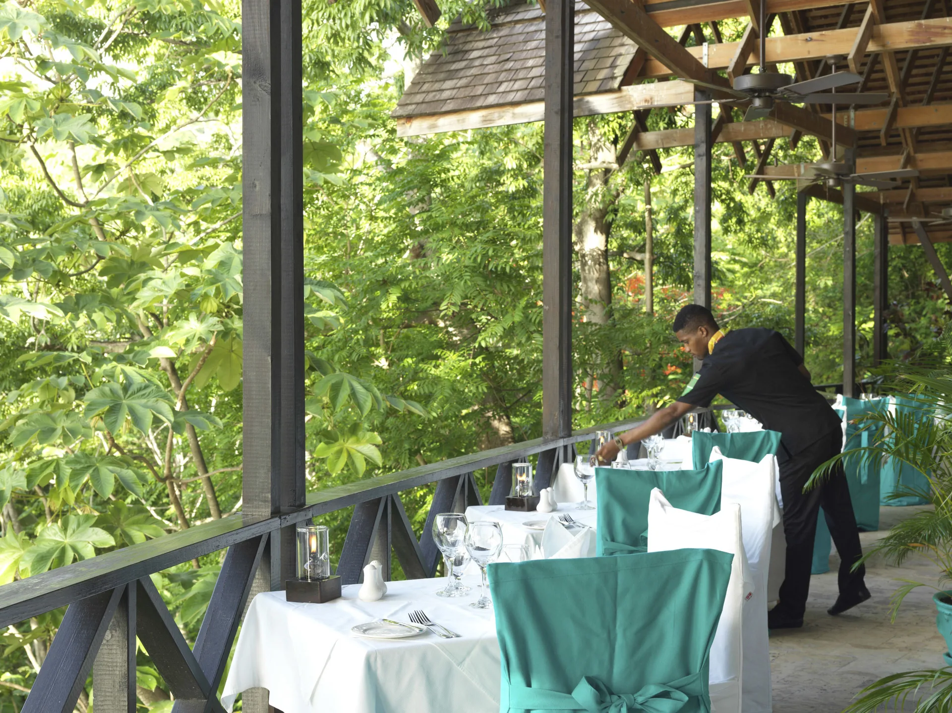Server adjusts a table on a forest-facing terrace at Anse Chastanet Resort.