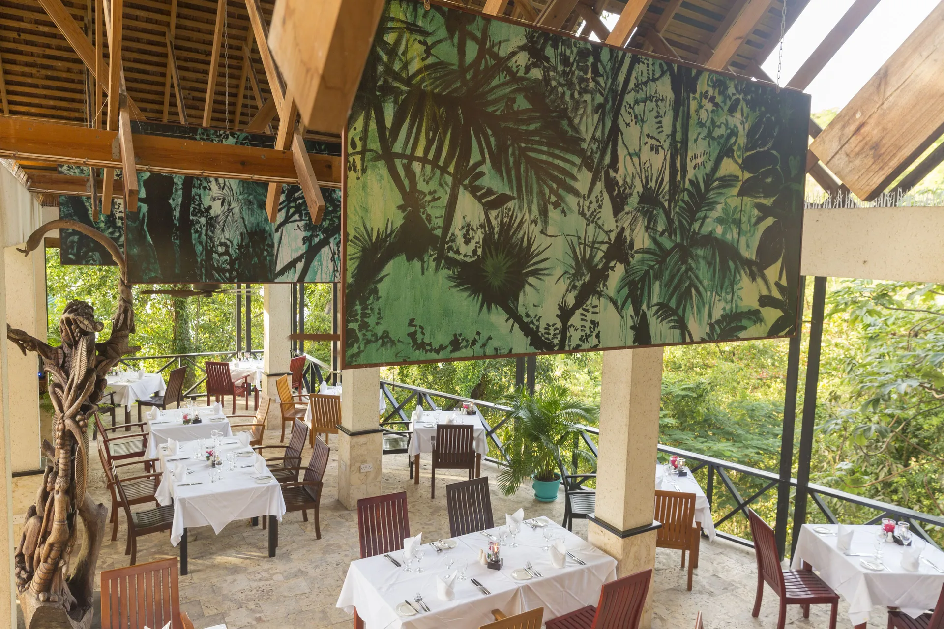 Open-air dining room with jungle panels and white table settings at Anse Chastanet Resort.