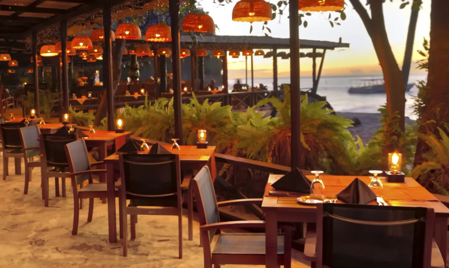 Beachside dining tables glow with lanterns at sunset at Anse Chastanet Resort.