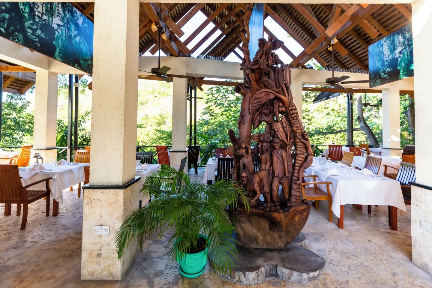 Open-air dining room with white tablecloths and a carved sculpture at Anse Chastanet Resort.