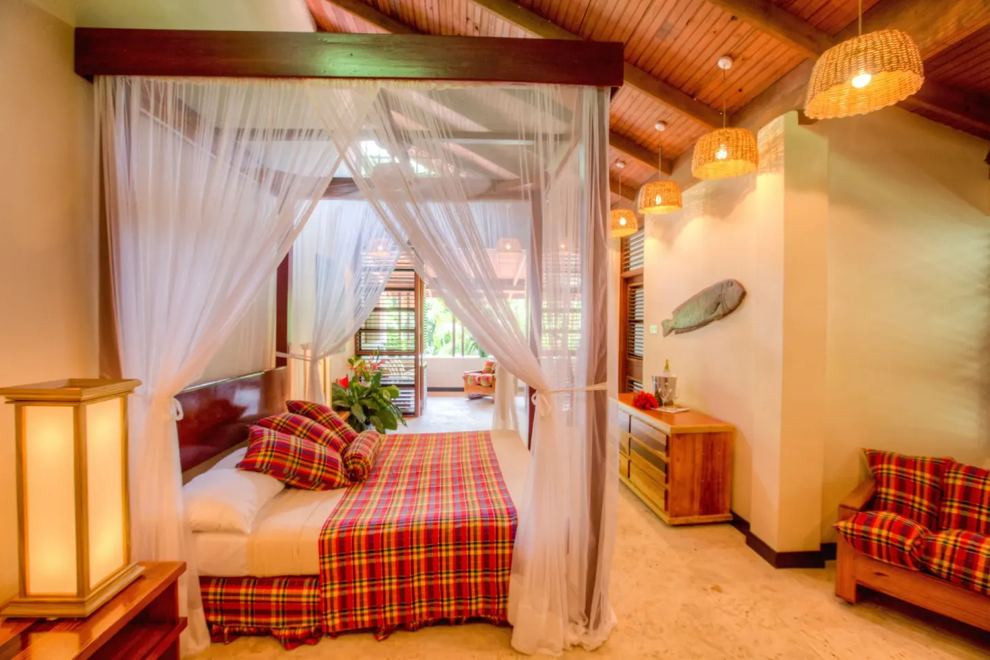 Deluxe Beachside Room with canopy bed, dresser, and wicker lights at Anse Chastanet Resort.