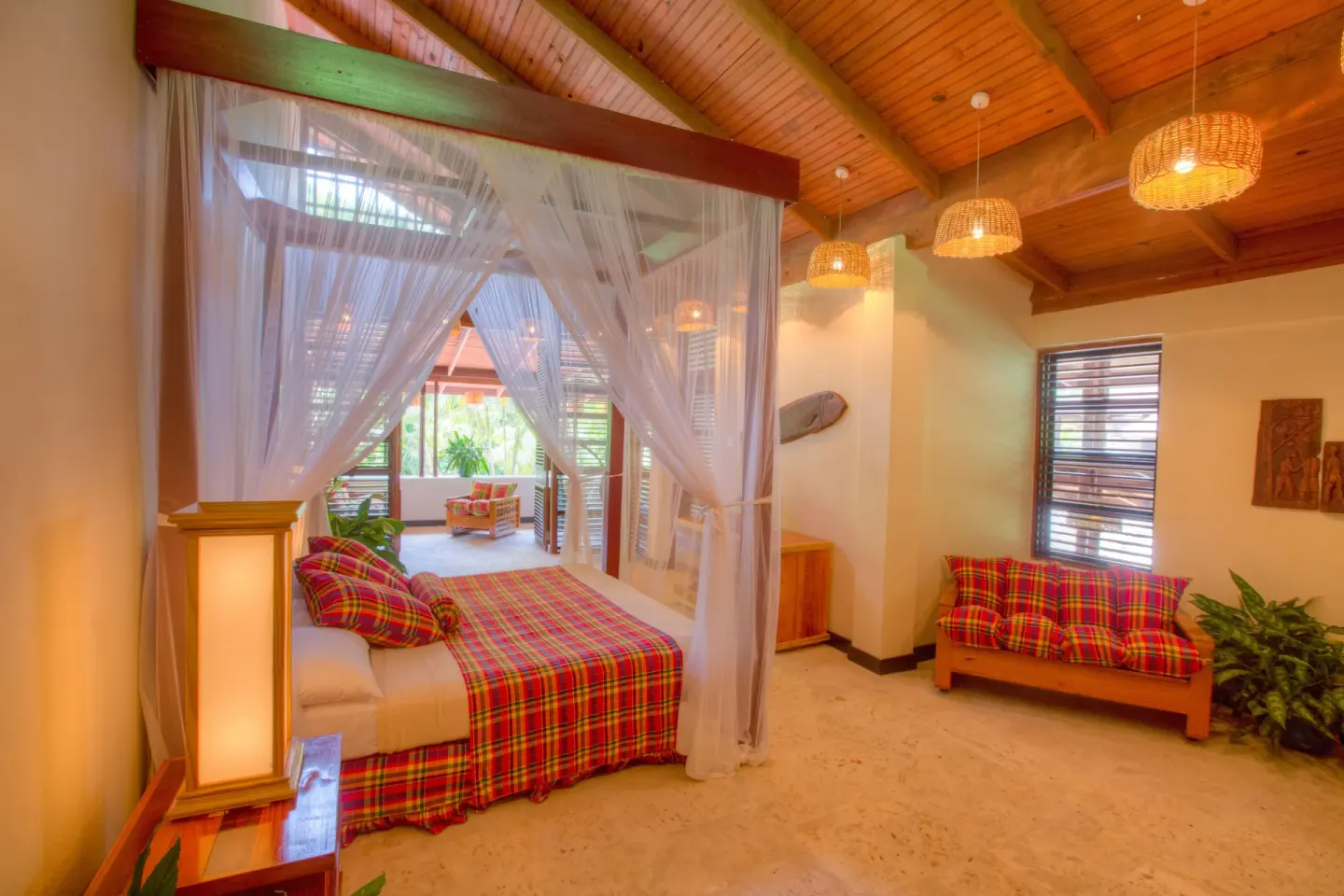 Deluxe Beachside Room with canopy bed, wood ceiling, and plaid sofa at Anse Chastanet Resort.