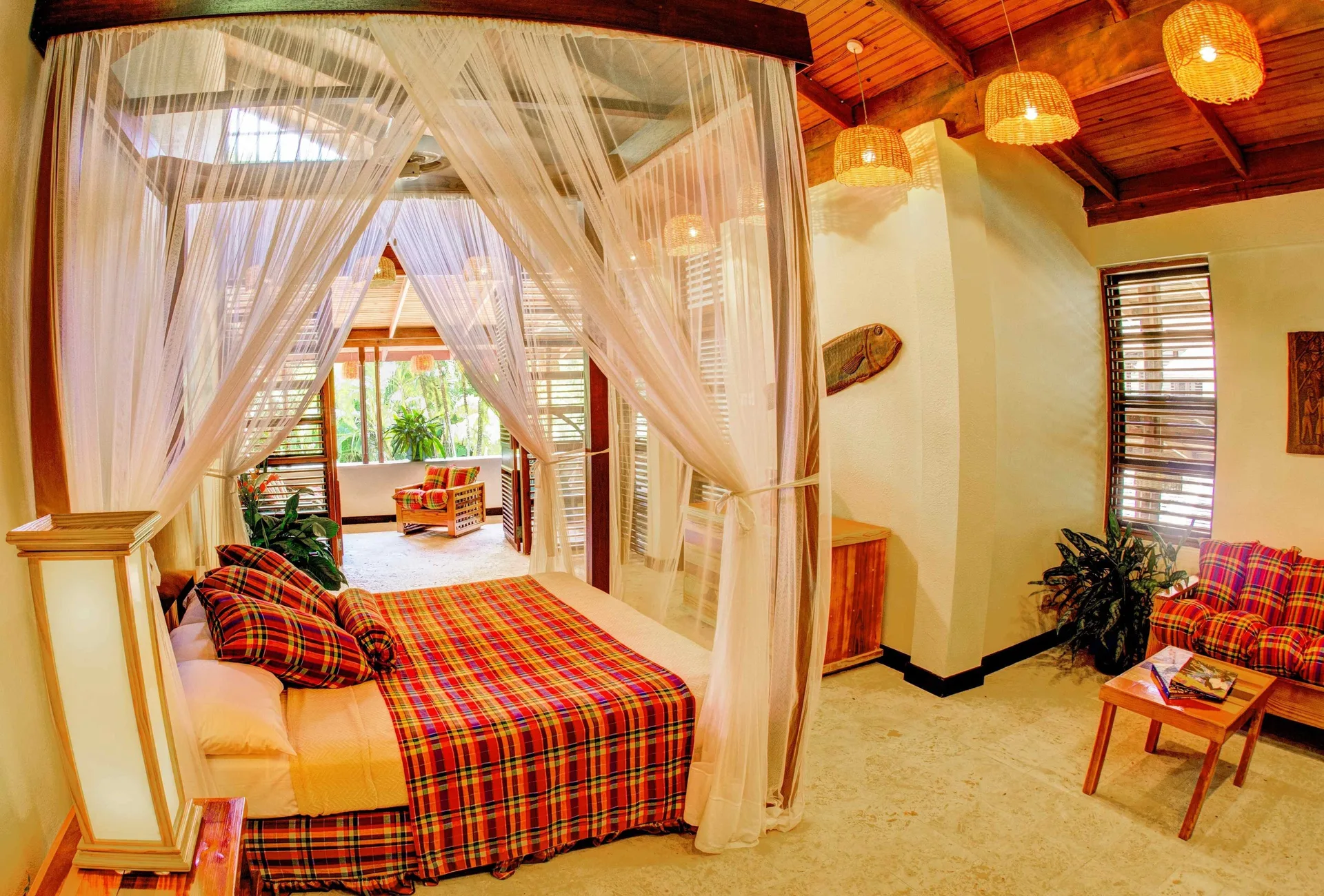 Deluxe Beachside Room with canopy bed and sitting area at Anse Chastanet Resort.
