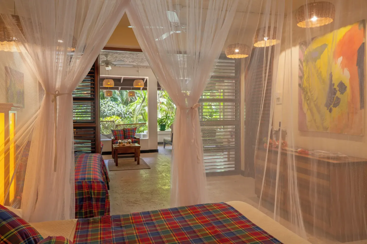 Deluxe Beachside Room bed seen through netting toward a tropical sitting area at Anse Chastanet Resort.