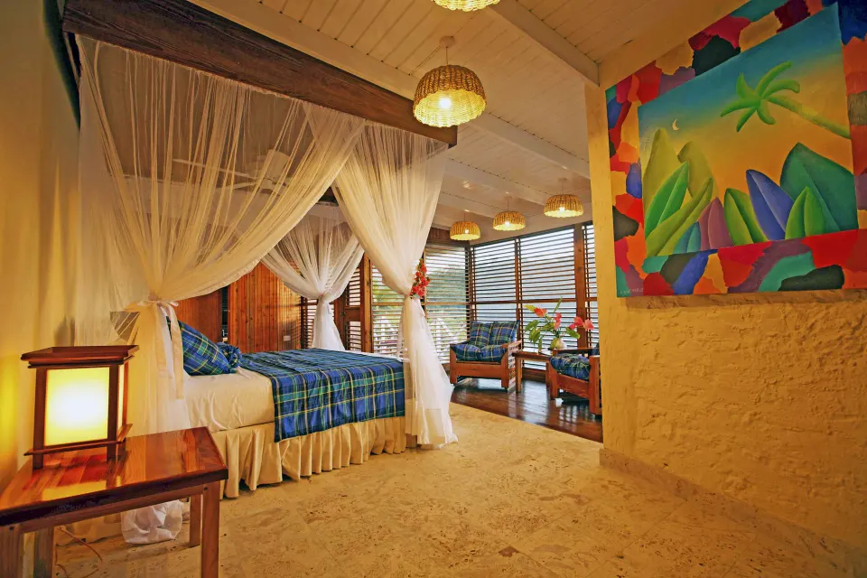 Standard Room with netted bed, colorful wall art and sitting area at Anse Chastanet Resort.