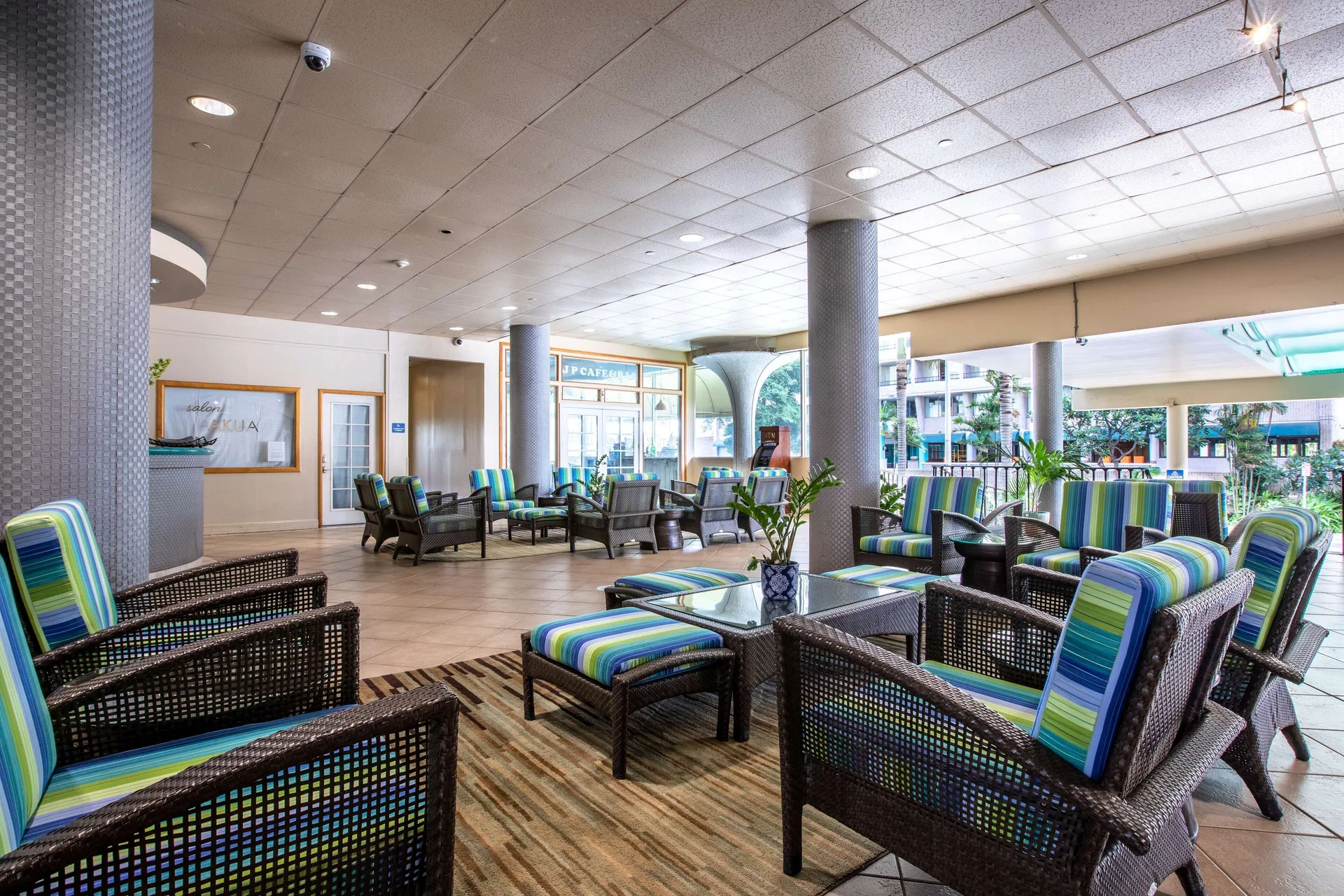 Covered lobby lounge with striped chairs and street-facing windows at Aqua Aloha Surf Waikiki.