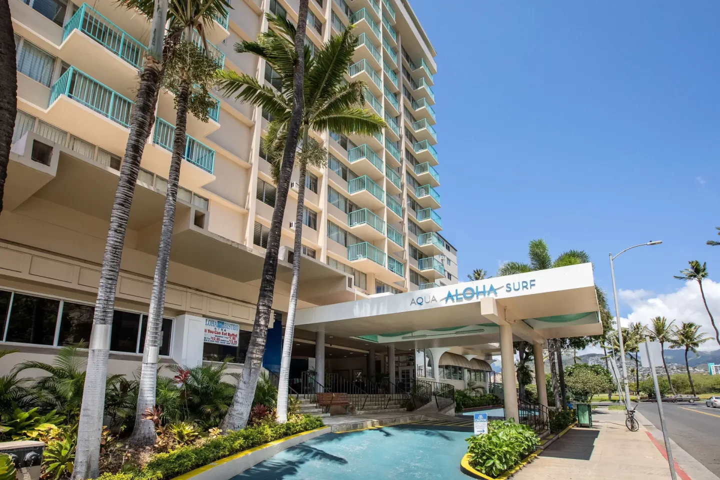 Entrance canopy and palm-lined exterior of Aqua Aloha Surf Waikiki.