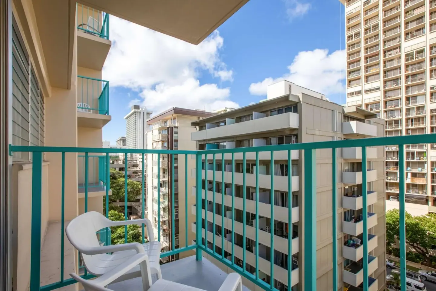 Guest balcony with white chairs and city buildings at Aqua Aloha Surf Waikiki.
