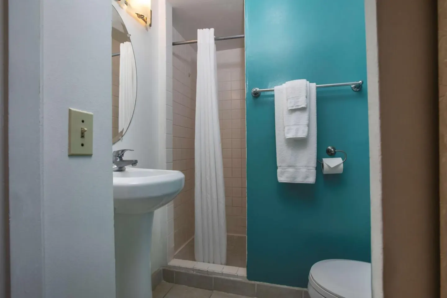 Compact bathroom with shower curtain and turquoise wall at Aqua Aloha Surf Waikiki.