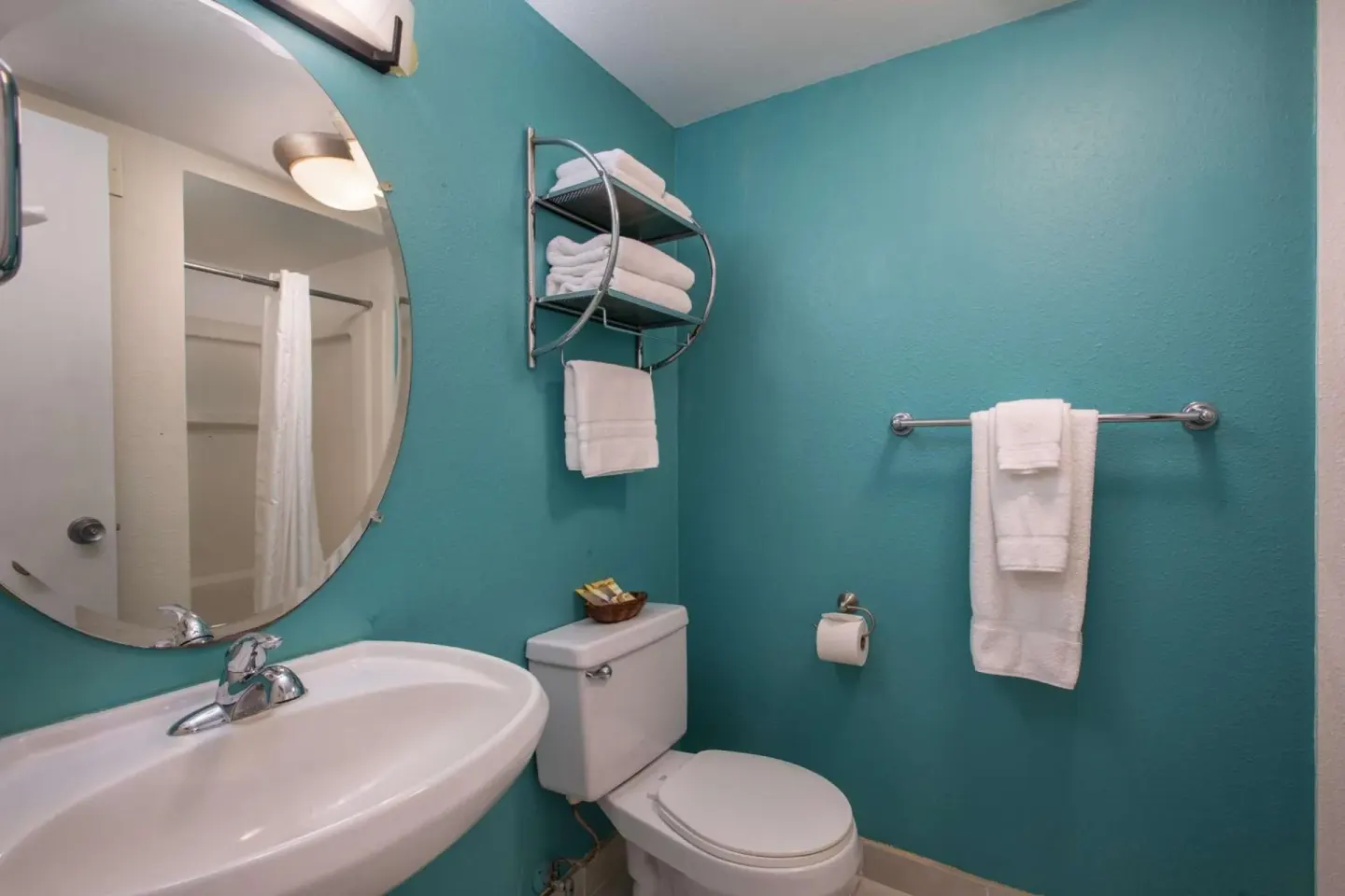 Bathroom vanity with towels and turquoise walls at Aqua Aloha Surf Waikiki.