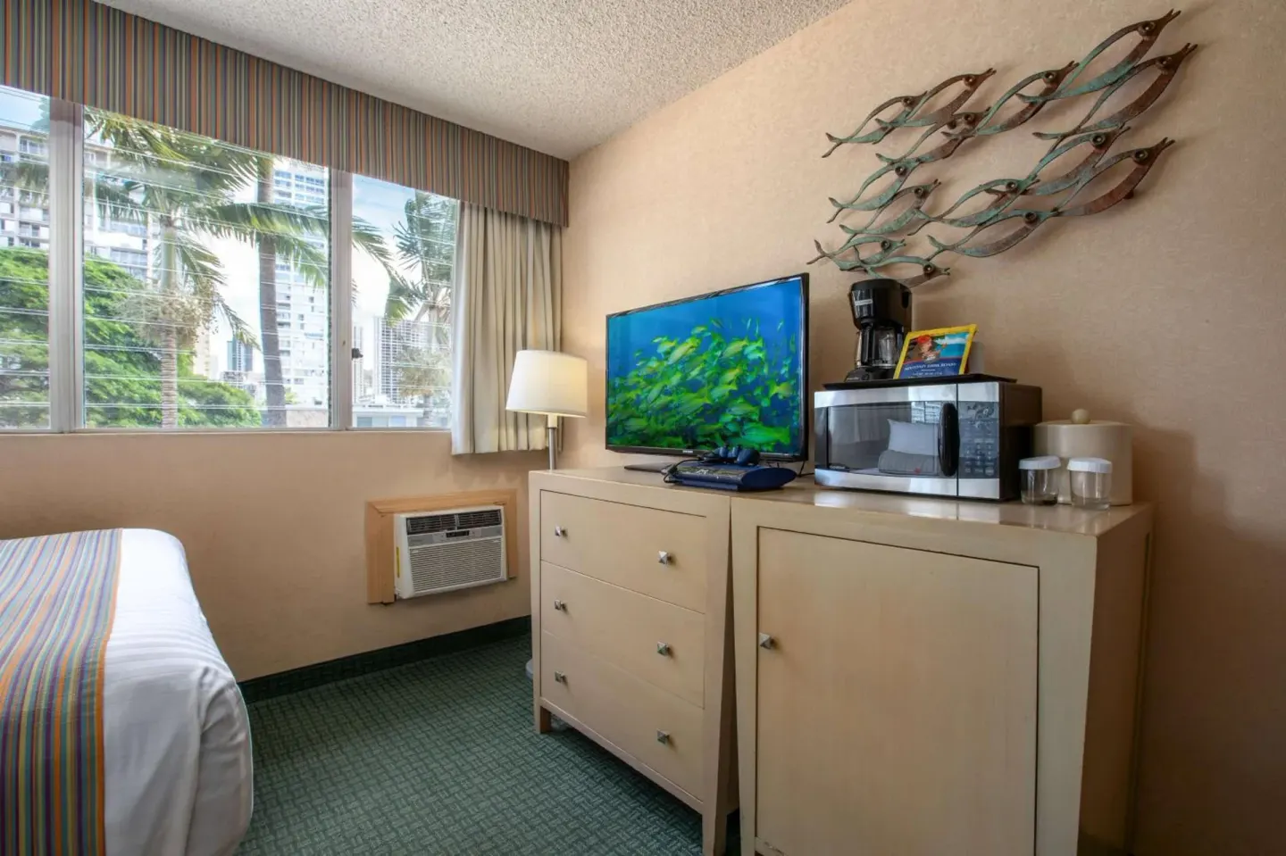 Guest room dresser with TV, microwave, coffee maker, and wall art at Aqua Aloha Surf Waikiki.