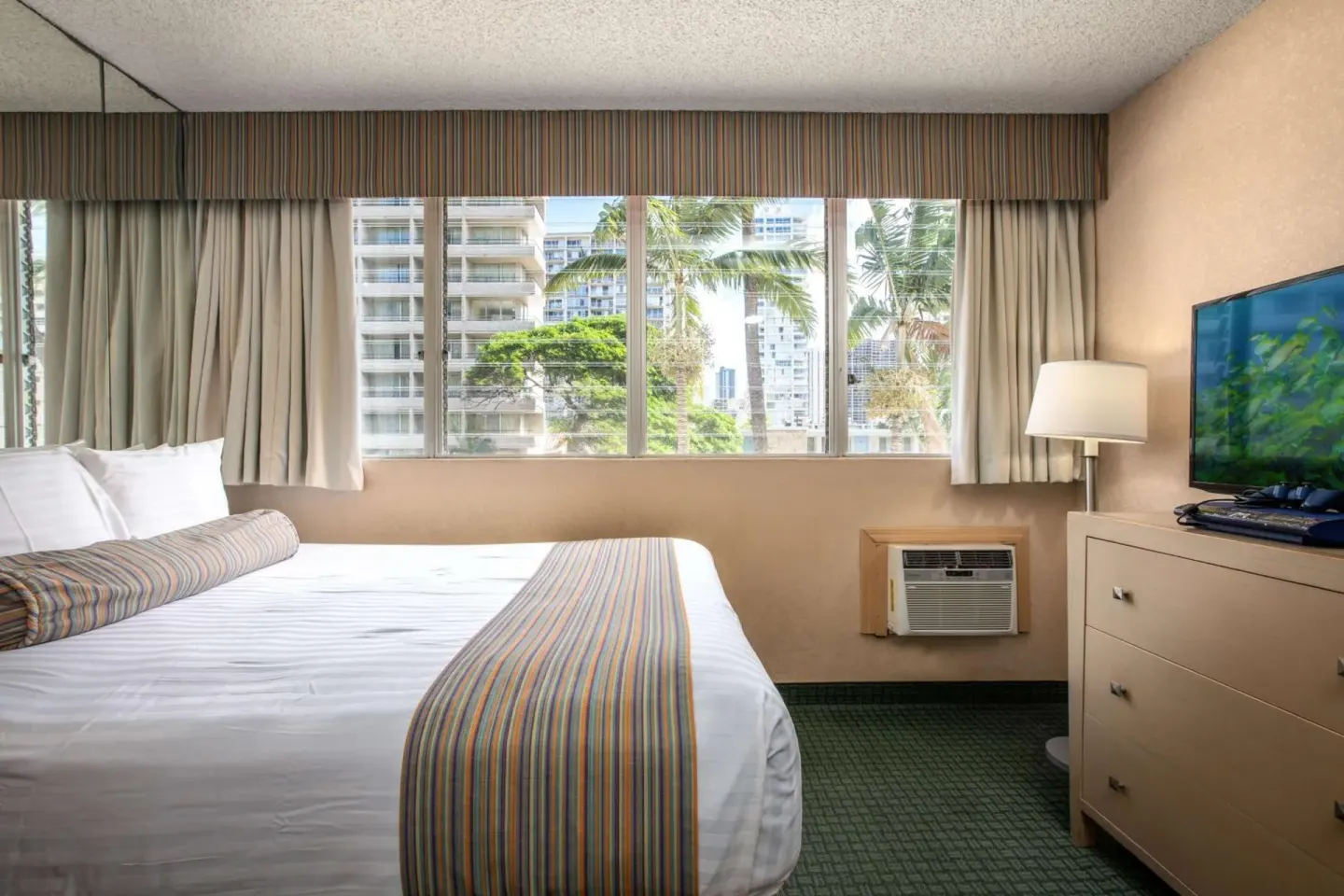 King bed guest room with city-facing windows at Aqua Aloha Surf Waikiki.